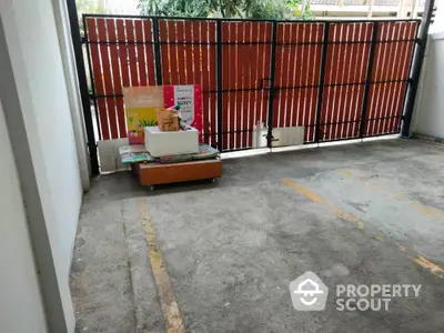 Spacious parking area with wooden fence and storage boxes, ideal for secure vehicle storage.