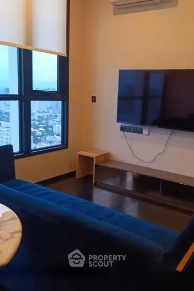 Modern living room with city view, featuring a sleek TV setup and stylish furniture.