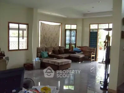 Spacious living room with large windows and comfortable seating in a cozy home.