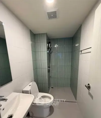 Modern bathroom with sleek shower and white fixtures in a contemporary apartment.