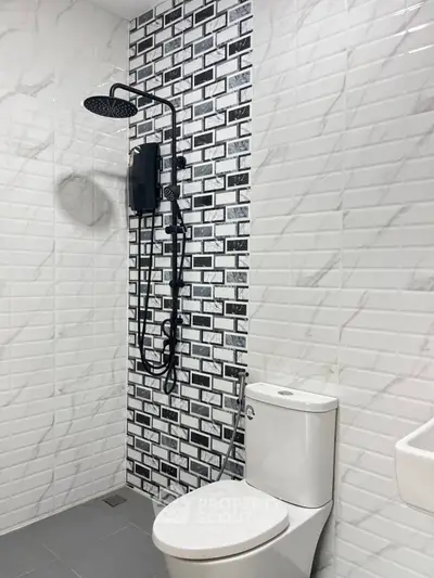 Modern bathroom with stylish black and white tiles and sleek shower design.