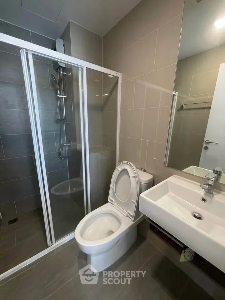 Modern bathroom with glass shower and sleek fixtures in contemporary apartment.