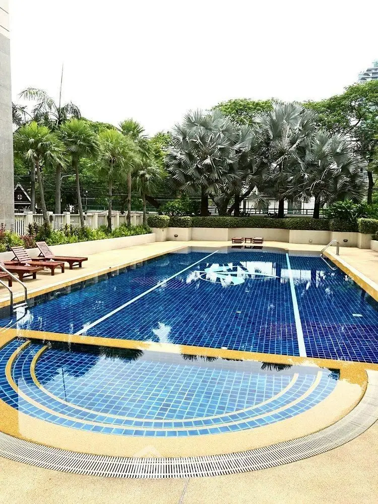 Luxurious outdoor swimming pool with lush greenery and sun loungers in a serene residential setting.