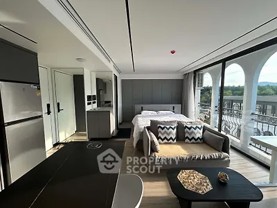 Modern studio apartment with open layout, featuring a cozy living area, bed, and kitchen with scenic balcony view.