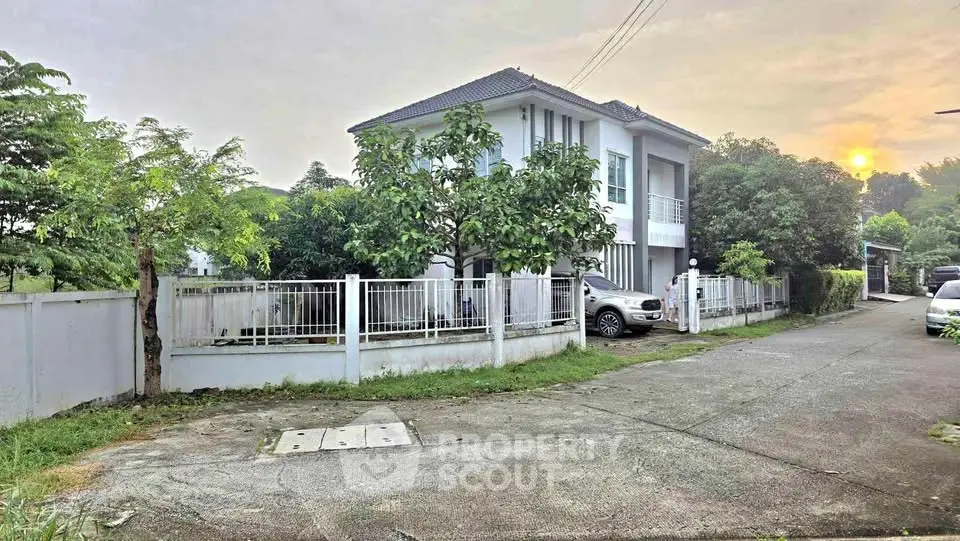 Charming suburban house with lush greenery and private driveway at sunset.