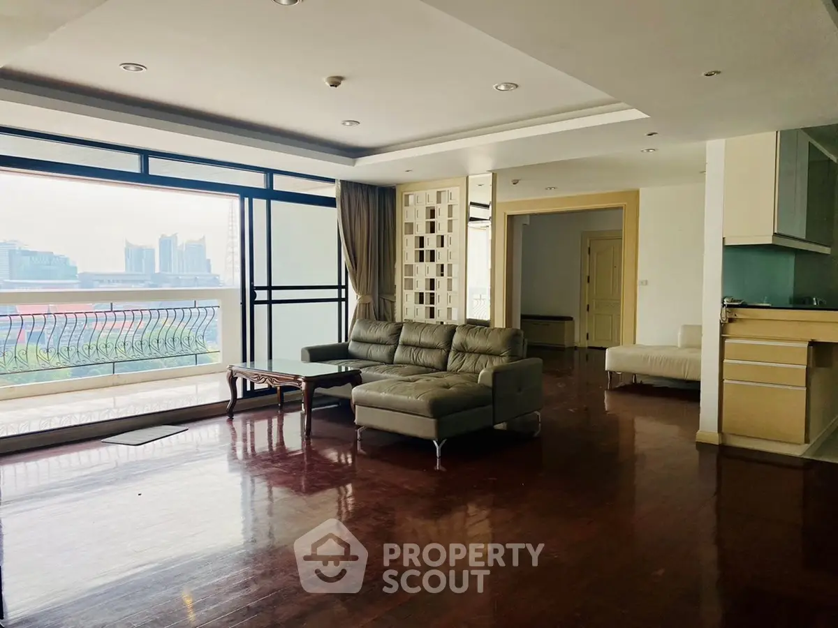 Spacious living room with modern furniture and city view balcony in luxury apartment.