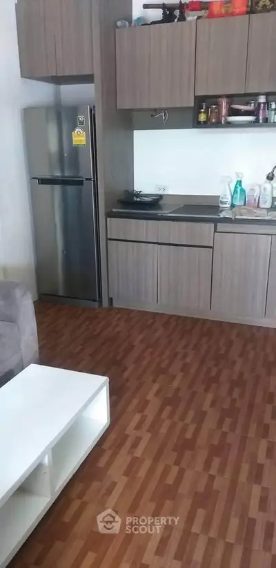 Modern kitchen with wooden cabinets and stainless steel fridge in cozy apartment.