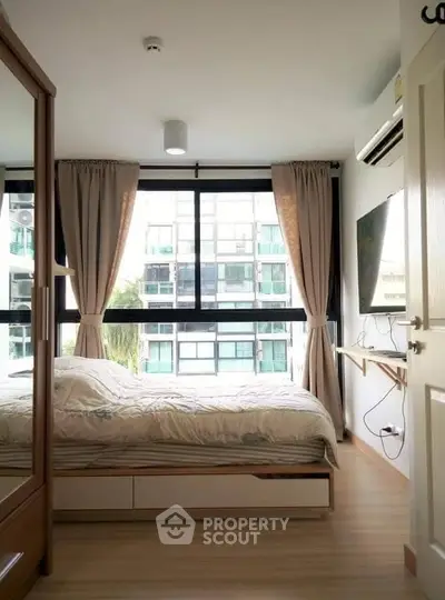 Cozy bedroom with large window and modern furnishings in urban apartment