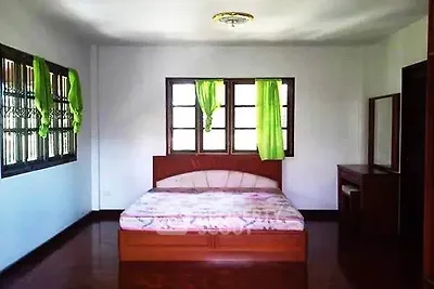 Spacious bedroom with wooden flooring and large windows for natural light.