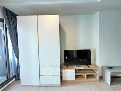 Modern living room with sleek white wardrobe and flat-screen TV on wooden stand.