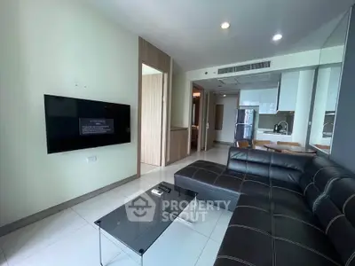 Modern living room with sleek black leather sofa and wall-mounted TV