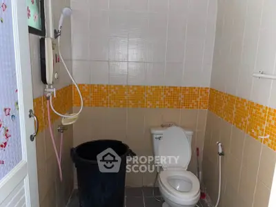 Cozy bathroom with modern shower and vibrant orange tile accents.