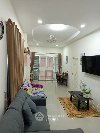 Spacious living room with modern decor and ample natural light, featuring a cozy seating area and dining space.