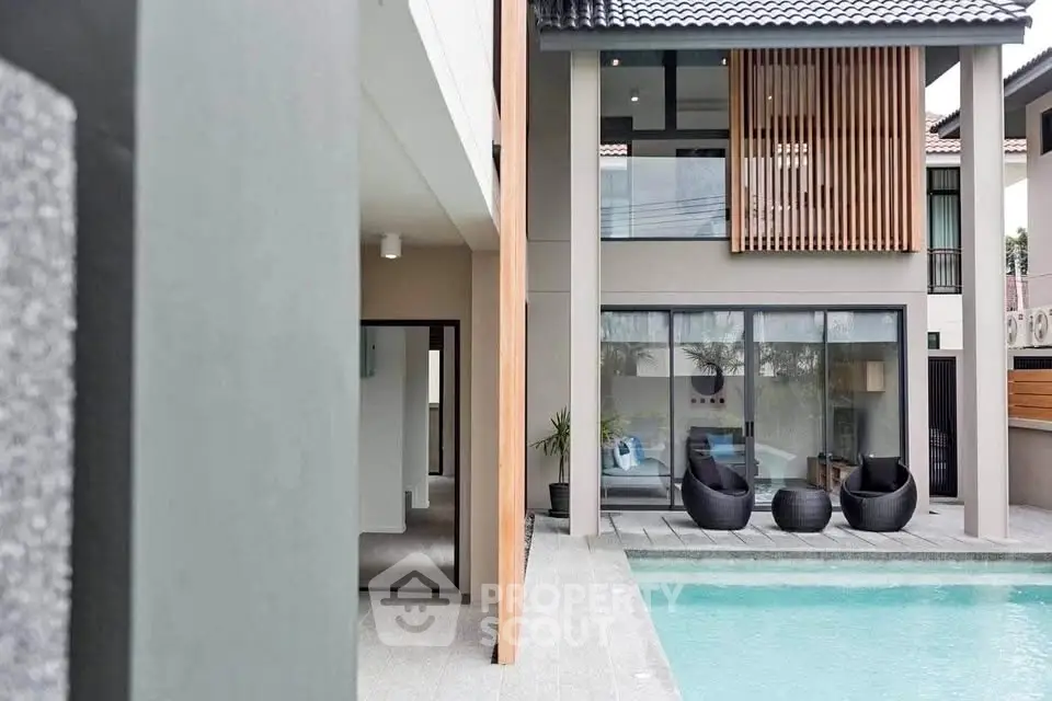 Modern luxury home with poolside view and stylish outdoor seating area.