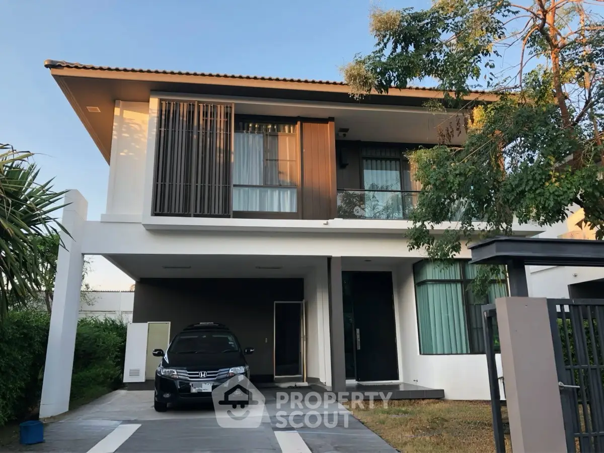 Modern two-story house with carport and lush greenery, perfect for family living.