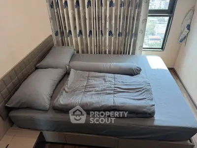 Cozy bedroom with modern decor and large window offering natural light and city view.