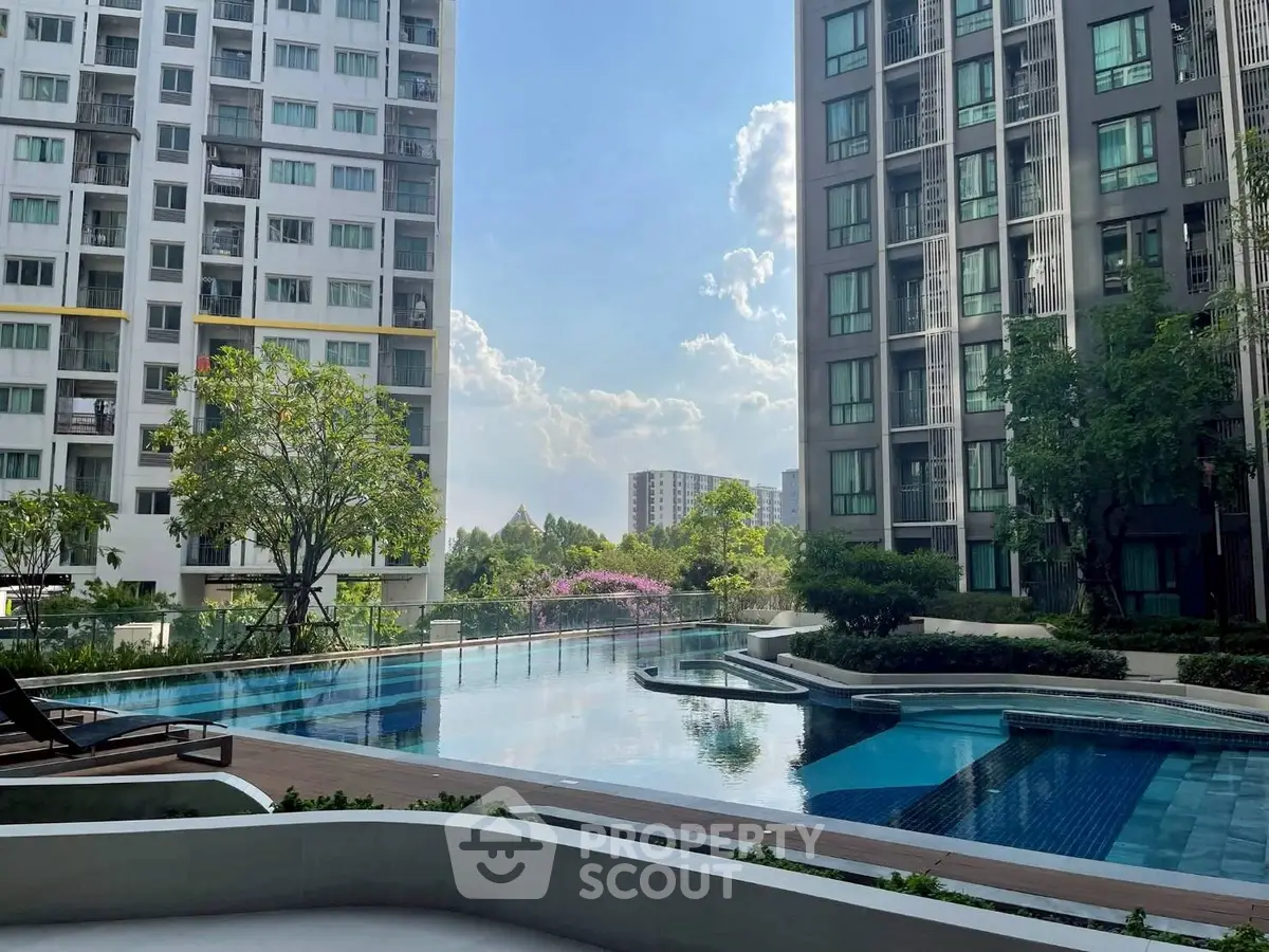 Luxurious condominium pool area with modern high-rise buildings and lush greenery.
