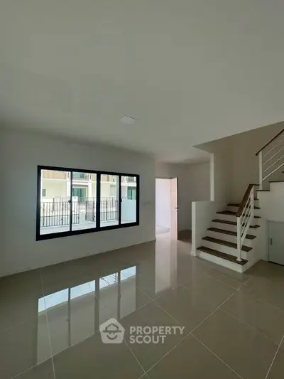 Spacious modern living room with glossy tiled floors and staircase