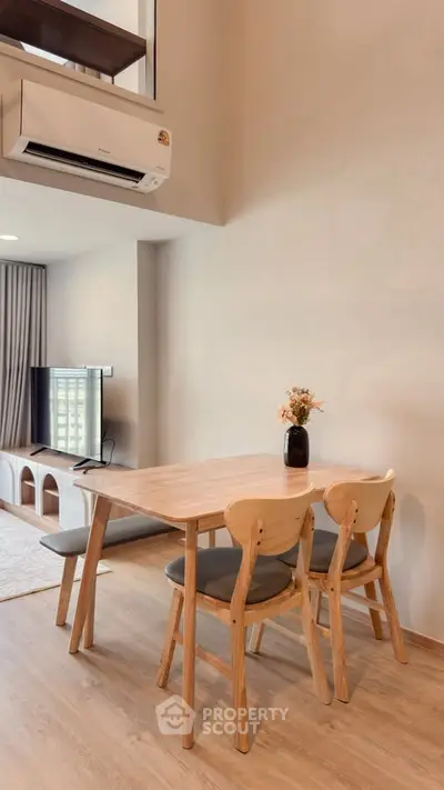 Modern dining area with wooden table and chairs, air conditioning, and TV in stylish apartment.