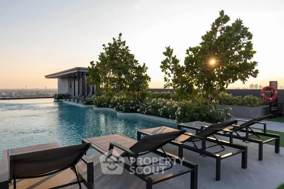Luxurious rooftop pool with sun loungers and stunning city view at sunset.