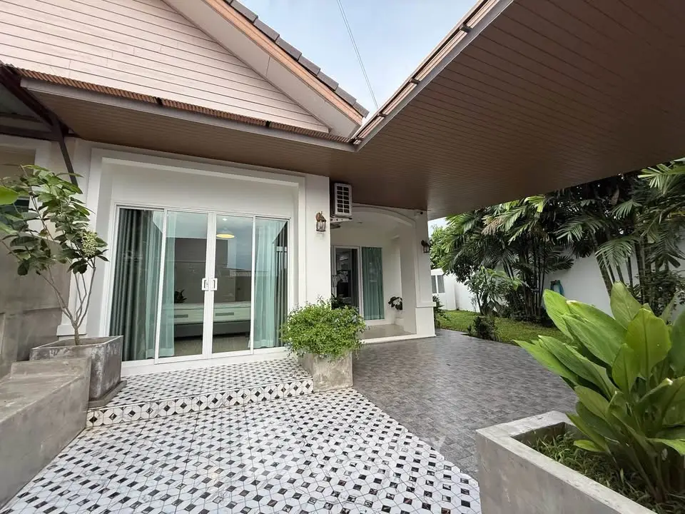 Charming modern home exterior with lush garden and stylish patio area, perfect for outdoor relaxation.