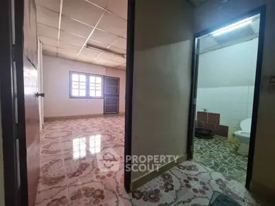 Spacious interior with tiled flooring and adjacent bathroom, ideal for renovation.