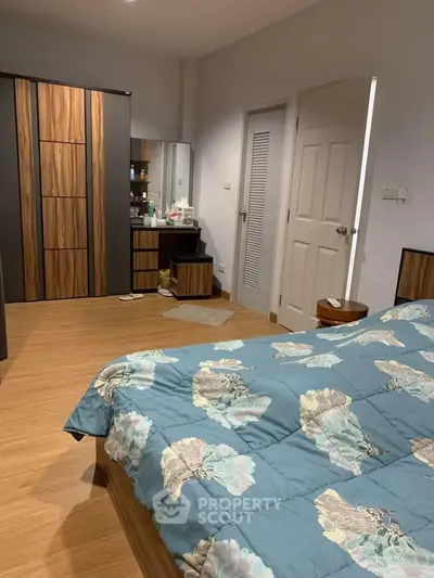 Cozy bedroom with stylish wooden wardrobe and floral bedding