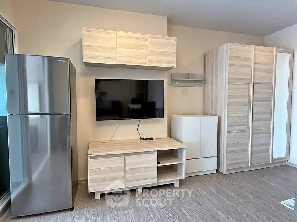 Modern living room with sleek furniture and stainless steel fridge in a cozy apartment.