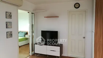 Cozy living room with modern TV setup and adjacent bedroom view