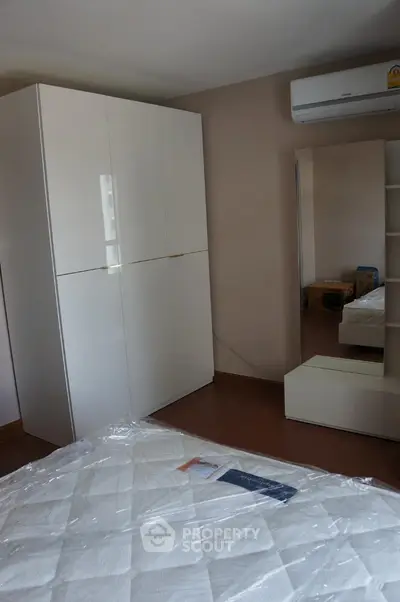Modern bedroom with sleek white wardrobe and air conditioning unit, perfect for comfortable living.