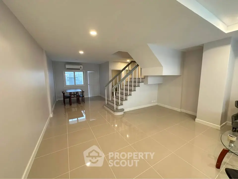 Spacious modern living room with sleek staircase and glossy tiled floors