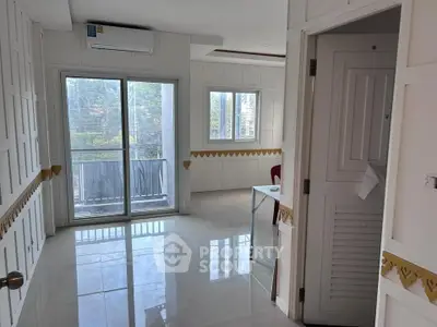 Bright room with large windows and balcony access, featuring elegant wall paneling and modern air conditioning.