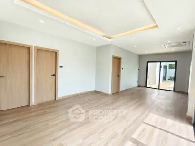 Spacious modern living room with wooden flooring and ample natural light.