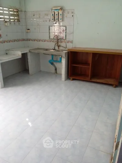 Spacious kitchen with tiled floor and basic cabinetry, ideal for renovation.
