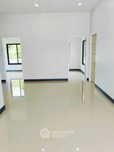 Spacious empty room with glossy tiled floors and large windows