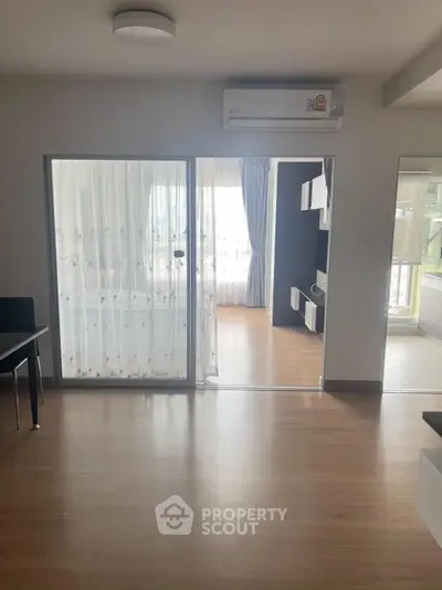 Spacious modern living room with wooden flooring and large windows for natural light.