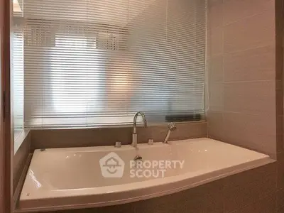 Luxurious bathroom with modern bathtub and frosted glass window for privacy.