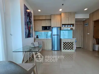 Modern kitchen with sleek wooden cabinets and glass dining table in a stylish apartment.