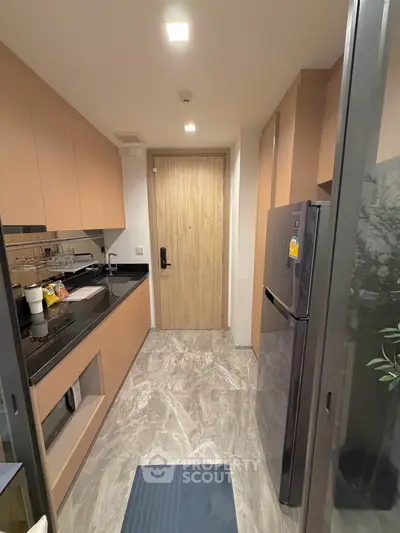 Modern kitchen with sleek cabinets and stainless steel fridge in a compact layout.