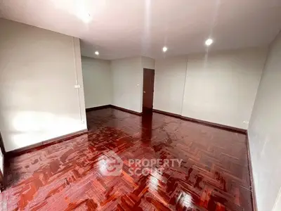 Spacious empty room with polished wooden floors and neutral walls, ideal for customization.