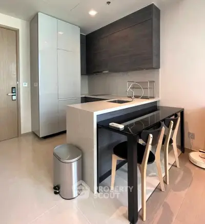 Modern kitchen with sleek cabinetry and dining area in contemporary apartment.