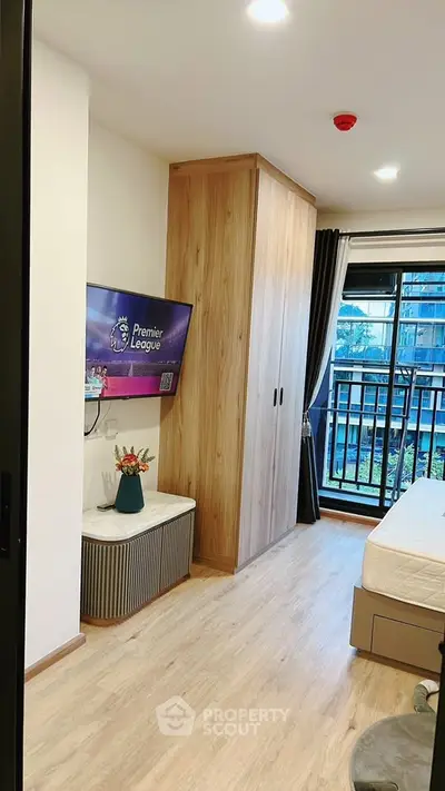 Modern bedroom with wooden flooring, built-in wardrobe, and balcony view in a stylish apartment.