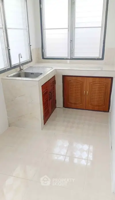 Compact kitchen with wooden cabinets and large windows for natural light