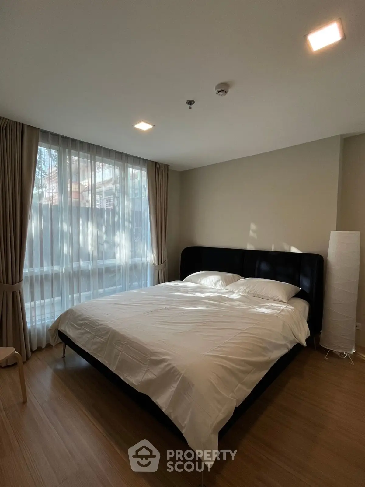 Spacious bedroom with large window and modern decor, perfect for relaxation and comfort.