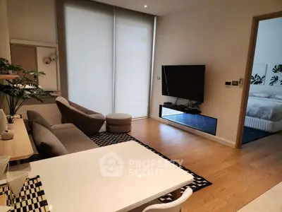 Modern living room with sleek furniture and wall-mounted TV, adjacent to a cozy bedroom.