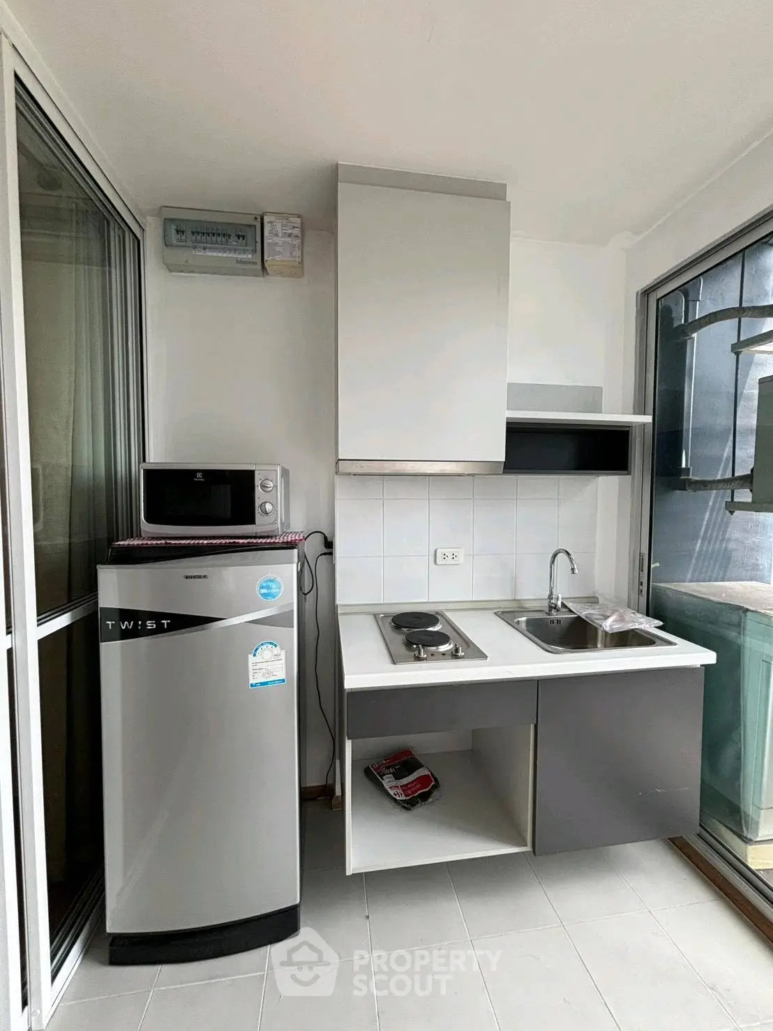 Compact modern kitchen with fridge, microwave, and electric stove in a bright apartment.