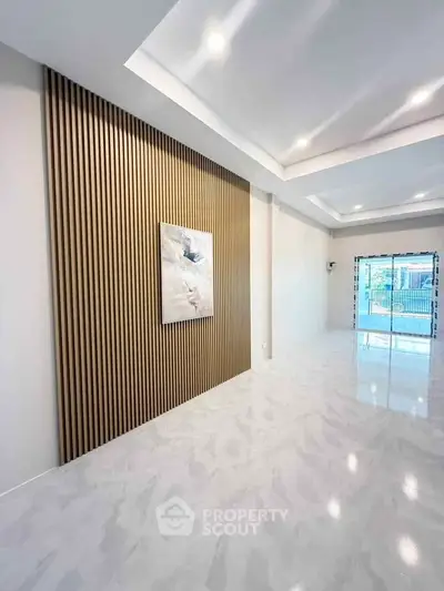 Spacious modern living room with elegant wall paneling and large windows for natural light.