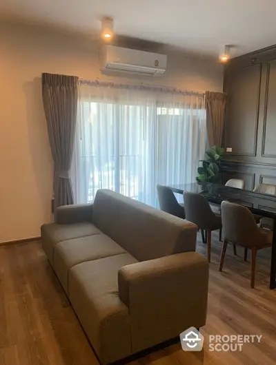 Modern living room with stylish sofa and dining area, featuring elegant curtains and wooden flooring.