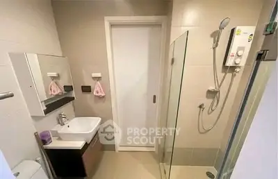 Modern bathroom with sleek design, featuring a glass shower enclosure and compact vanity unit.