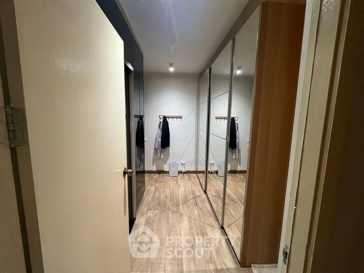 Spacious walk-in closet with mirrored sliding doors and wooden flooring